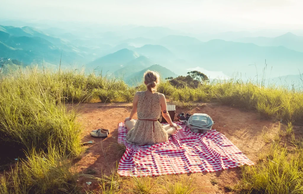 A lady on a picnic mat looking at the beautiful overlooking scenery contemplating on housing move